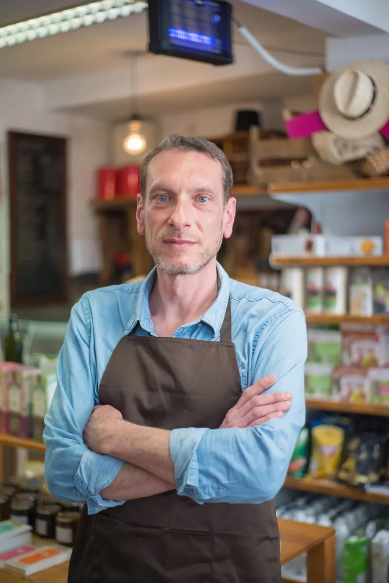 A grocer in an apron standing in his store