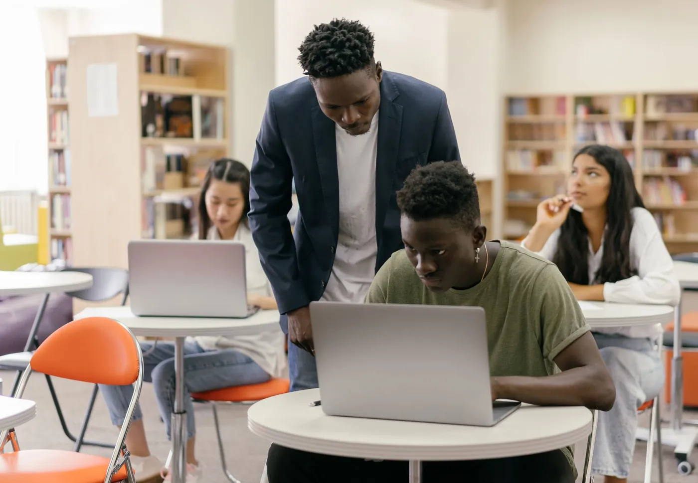 A tutor helping students working on laptops